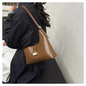 Close-up of brown glossy leather shoulder bag with elegant gold square buckle detail