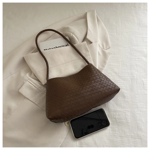Detailed view of dark brown woven leather hobo bag on a chic cream blazer
