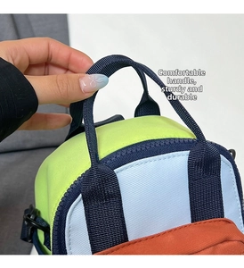 Detail of color-block mini bag showing double zippers and reinforced webbing handles