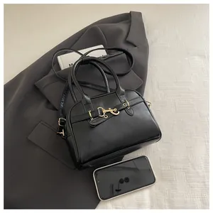 Detail of black faux leather tote with golden horsebit buckle and adjustable strap