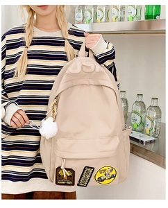 Detail of beige nylon school backpack featuring USA embroidery and vintage patches