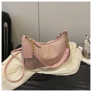 Sac à main tissé rose avec chaîne dorée sur table noire avec écharpe et café