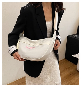 Detail of white nylon crescent bag with pink fashion logo and adjustable strap on a model