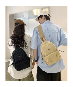 Detail view of mini nylon backpacks in black and beige with adjustable side drawstrings