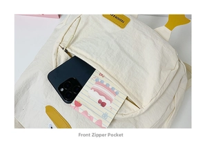 Detail view of the front zipper pocket on a white nylon backpack showing storage space