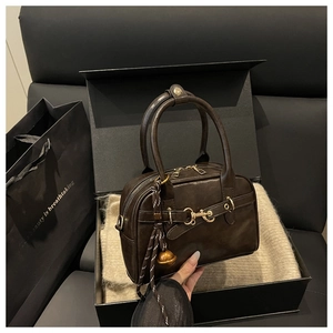 Detail of vintage brown leather Boston bag with metal buckle and round charm in a gift box