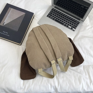 Corduroy puppy backpack with long ears and laptop displayed on white fabric surface