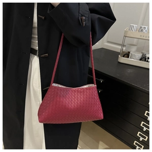 Dettaglio macro della trama in pelle intrecciata rosso scuro e fodera interna della borsa