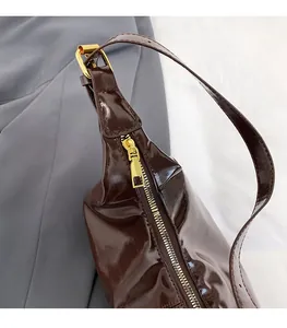 Detail der dunkelbraunen Lackleder-Handtasche mit hochwertigem goldfarbenem Reißverschluss