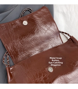 Détail de boucle magnétique argentée et cuir froissé brillant sur sac à bandoulière marron
