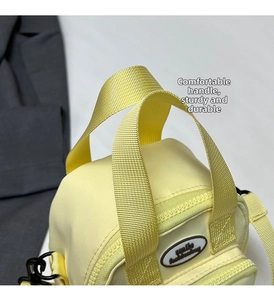 Detail of yellow canvas tote bag handles and smile fashionbag label on front pocket