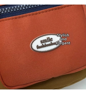 Detail of orange nylon bag texture featuring smile fashionbag logo and blue zipper