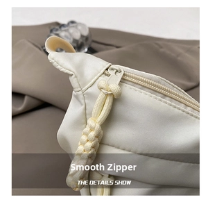 Close-up of a white nylon crossbody bag featuring a smooth zipper with woven rope puller