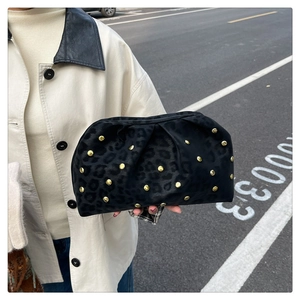 Detail of velvet leopard print clutch bag with gold studs in an outdoor street setting