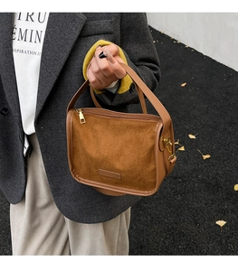 Detail of vintage caramel suede handbag with gold zipper and leather trim in autumn setting