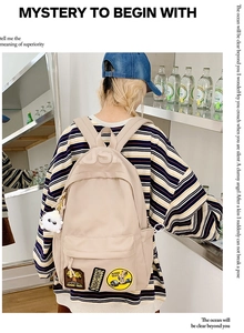 Close-up of beige nylon backpack featuring relief USJ letters and vintage embroidery patch