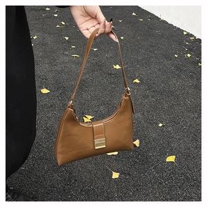 Close-up of brown leather shoulder bag featuring a vintage gold buckle and zipper closure