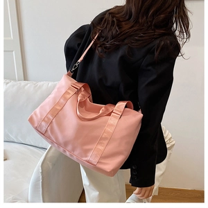 Pink waterproof travel bag shown worn as a crossbody on a model with suit jacket