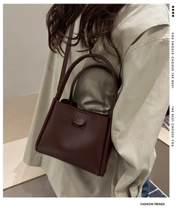Detail view of the deep brown leather texture and magnetic flap closure on the bucket bag