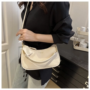 Detail der beigen Hobo-Tasche mit Webmuster, Riemen und dekorativer Metallkette