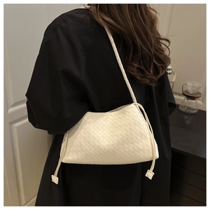Detail of cream woven shoulder bag with fine leather texture and decorative side drawstrings