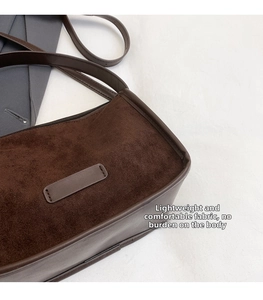 Close-up of deep brown matte suede fabric texture and leather strap of the shoulder bag
