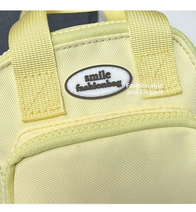 Macro detail of high-quality light yellow fabric bag with smile fashionbag logo embroidery