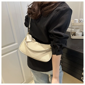 Détail d'un sac hobo tissé beige avec bandoulière en cuir et finitions dorées sur modèle