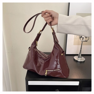 Détail du sac hobo en cuir verni bordeaux avec finition brillante et ferrures dorées