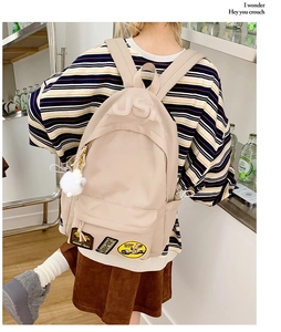 Detail of cream backpack featuring USA embossed logo and retro decorative patches