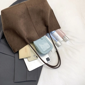 Deep brown large-capacity suede tote bag with slim shoulder straps on a grey suit
