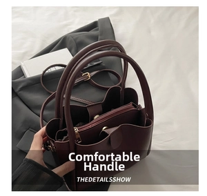 Detail of dark burgundy handbag featuring golden hardware and adjustable leather strap