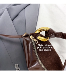 Detail of dark brown suede handbag with large gold chain buckle and leather splicing