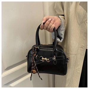 Detail of vintage black leather Boston bag with golden horsebit and woven tassel charm