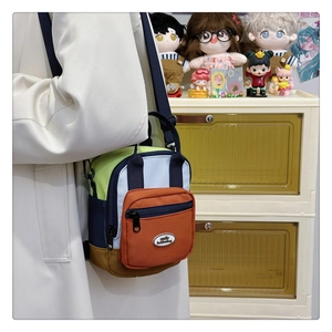 Close-up of multicolor patchwork crossbody bag with orange zip pocket and black strap