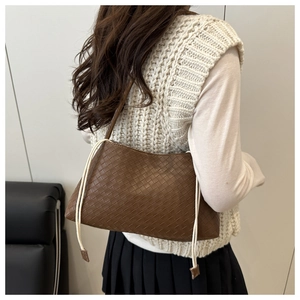 Detail of dark brown woven leather shoulder bag with contrasting cream drawstring cords