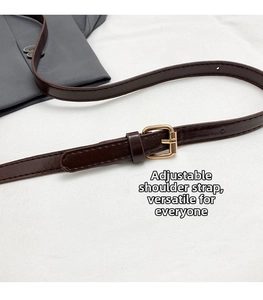 Macro detail of dark brown leather adjustable shoulder strap with gold metal buckle