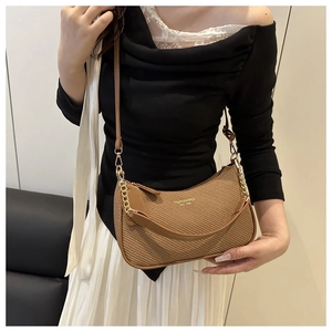Detail of coffee-colored woven Hobo bag with gold lettering and metal chain strap
