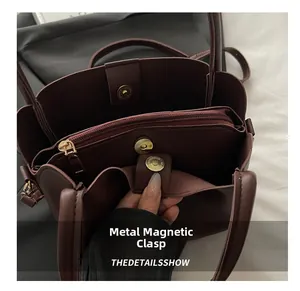 Detail of burgundy PU handbag featuring multiple compartments and metal magnetic snap closure