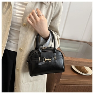 Close-up of a vintage black leather handbag with gold horsebit hardware detail