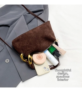 Detail view of brown suede baguette bag with gold chain buckle and daily essentials inside