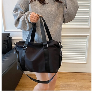 Detail of a large black waterproof nylon tote bag with adjustable shoulder strap and metal hardware