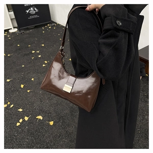Detail of dark brown glossy hobo bag with metallic buckle closure on shoulder