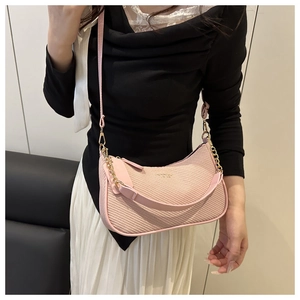 Detail of pink woven half-moon bag featuring gold chain strap and textured fabric