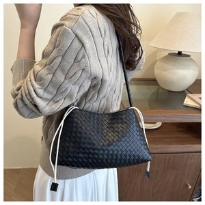 Detail of black woven shoulder bag with white drawstring accents and braided straps