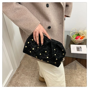 Close-up of black leopard embossed clutch bag with gold studs and pleated texture