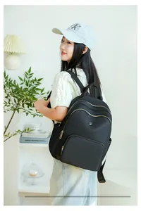 Detail of black nylon backpack featuring gold zippers and multiple storage compartments