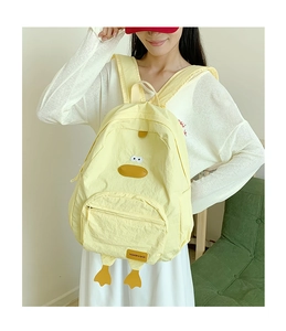 Detail of yellow duck backpack showing canvas texture, embroidery and brand logo
