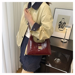 Close-up of elegant burgundy shoulder bag featuring shiny leather and metal buckle detail