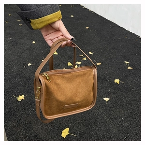 Outdoor shot of caramel suede handbag with golden zipper and leather handle details